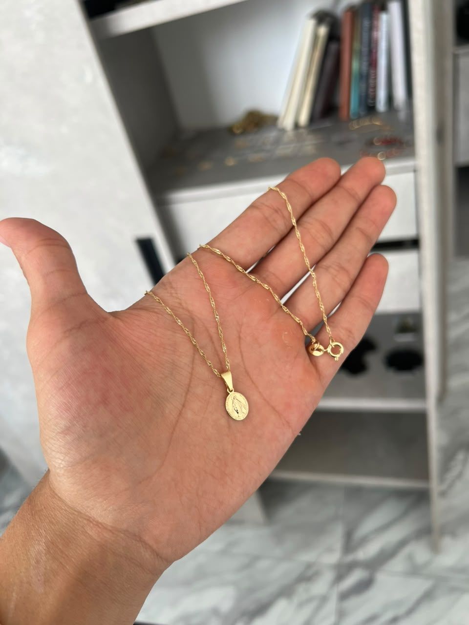 Cadena Singapur con dije en la mano